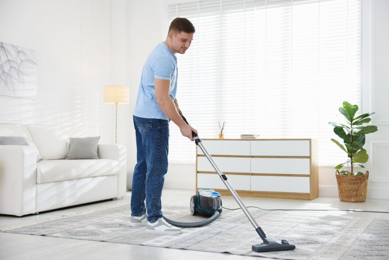 Reinigungskraft von cleanteam bei der sorgfältigen Teppichreinigung in einem privaten Wohnzimmer in Laupheim